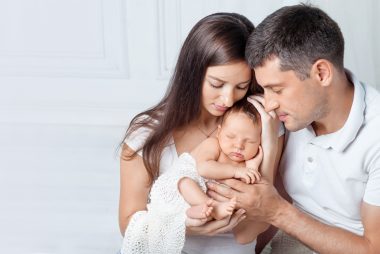 Woman and man holding a newborn. Mom, dad and baby.
