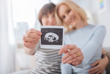 ultrasound photo being held by a joyful nice female couple